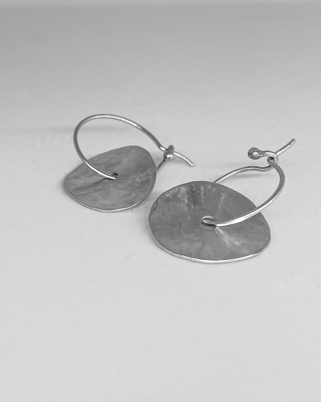 A pair of discs of Sterling Silver that sits on a hoop earring