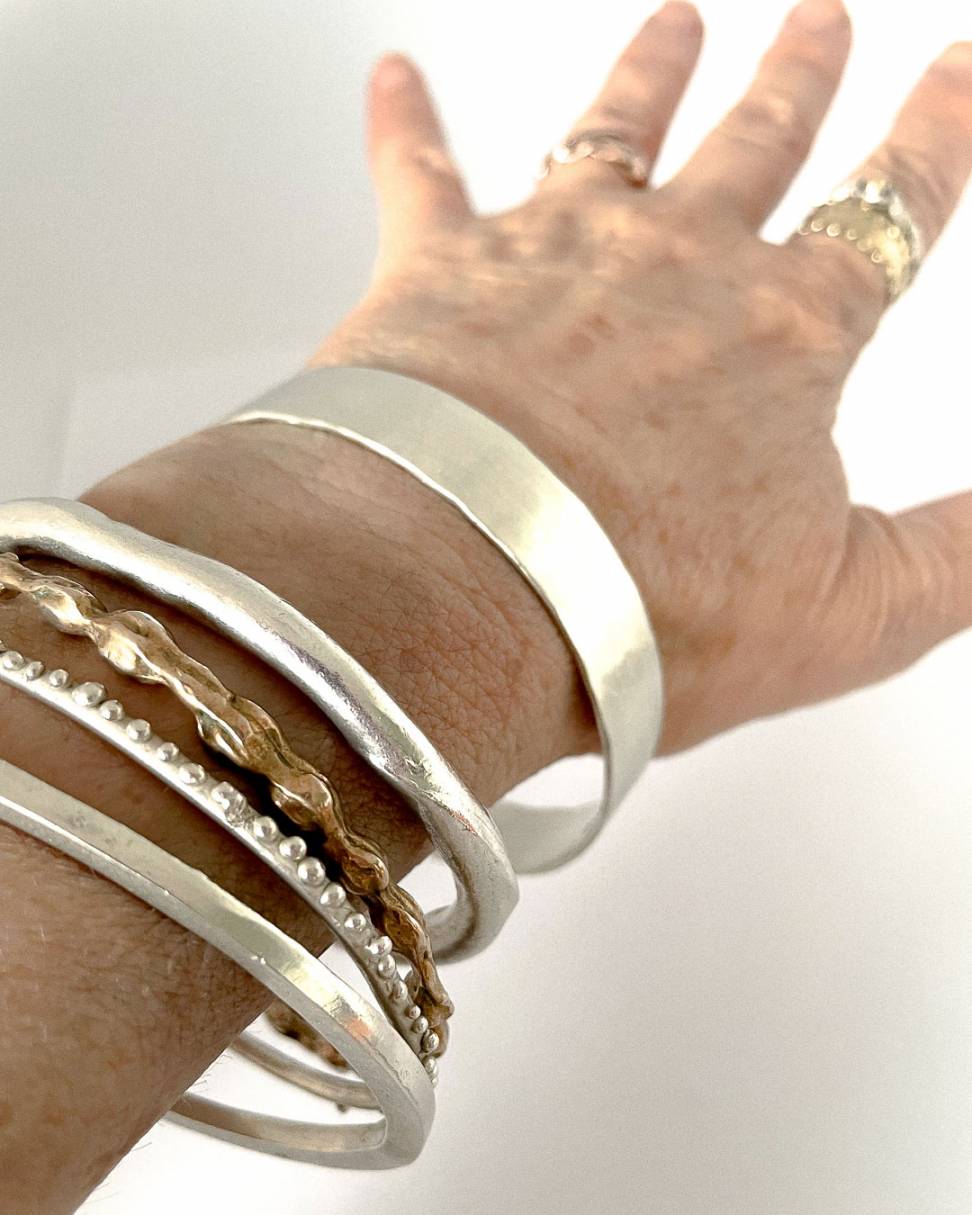 A collection of Bangles being worn including the Heavy Textured Unisex Bangle - standard width
