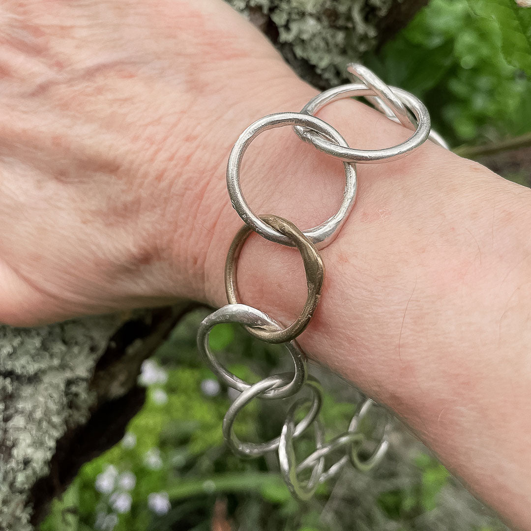 A hand resting against a branch showing the Sun and the Moon Chain Bracelet being worn