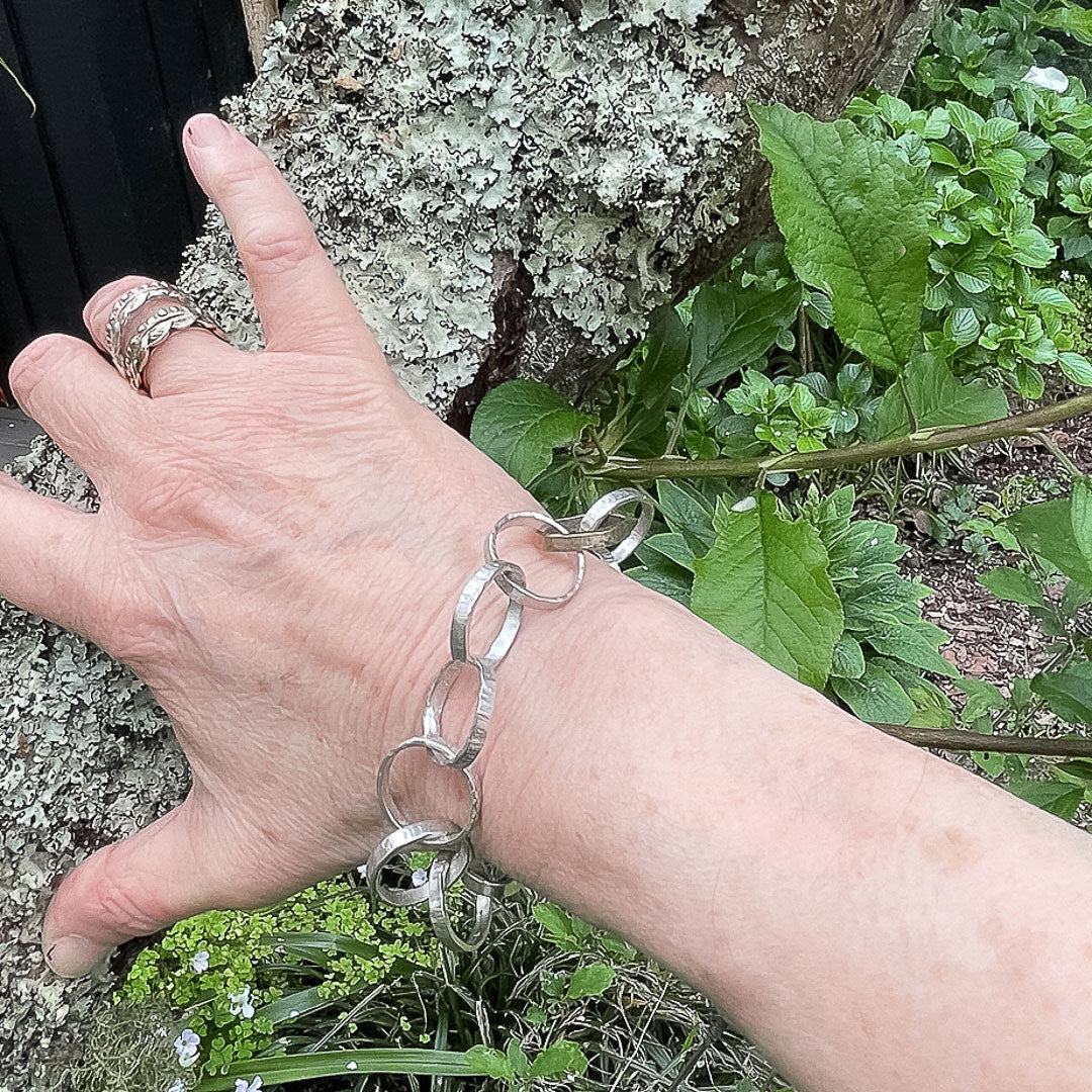A hand resting against a branch showing the Heavy textured Link Chain Bracelet being worn