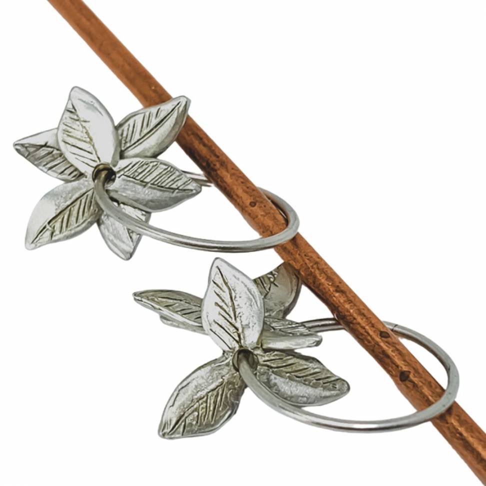 A pair of Sterling Silver Fire-Star Flower Hoop Earrings with the flowers crafted from two petal layers that curve around each other and hang from a small hoop earring