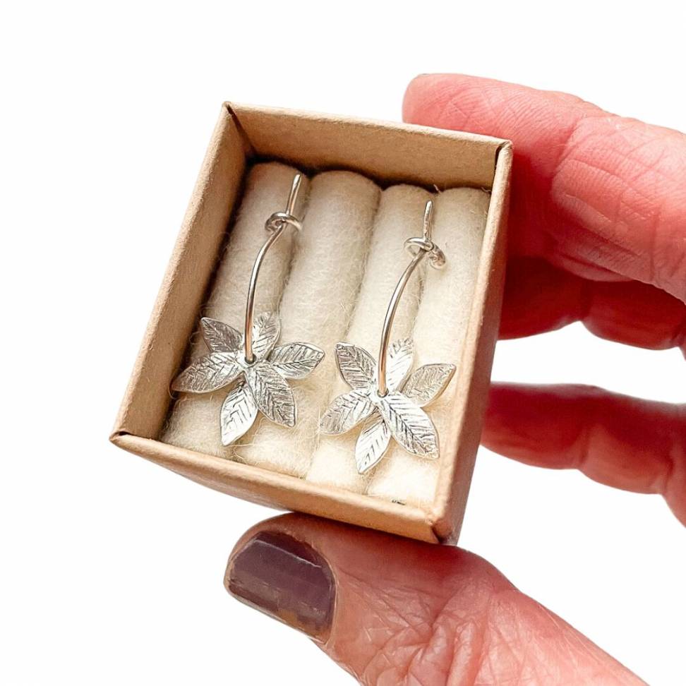 A pair of Sterling Silver Fire-Star Flower Hoop Earrings held in a presentation box