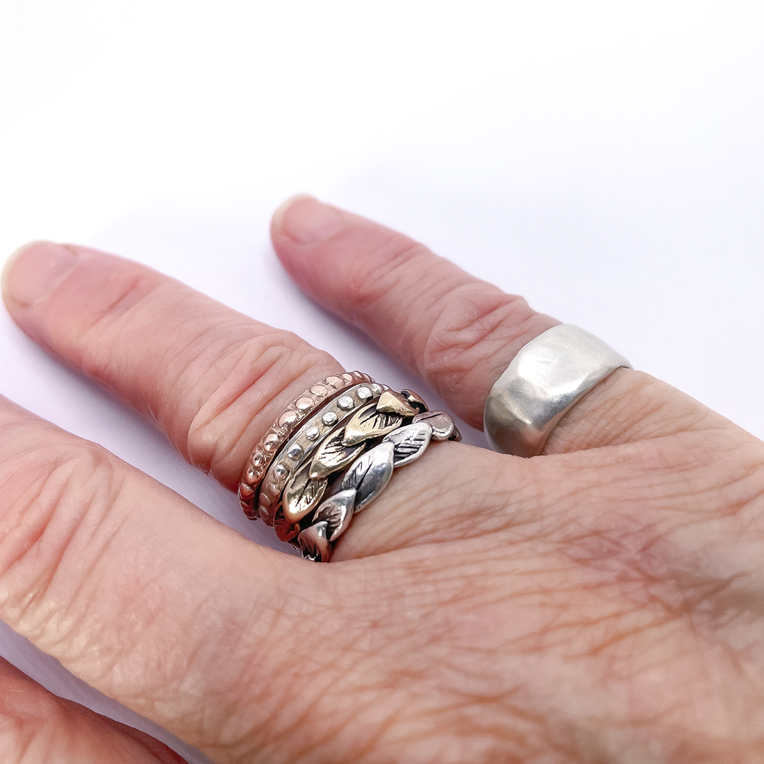hand wearing stacking rings and organic fluid ring