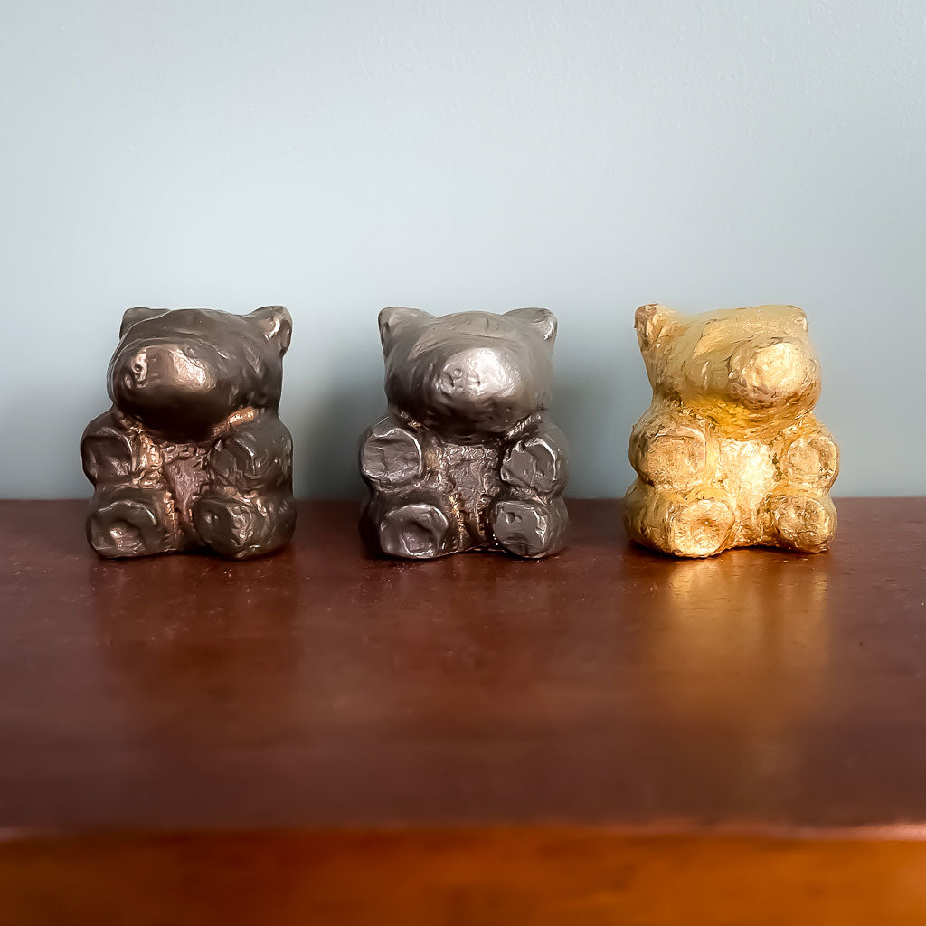 Three small bronze bears sitting on a shelf