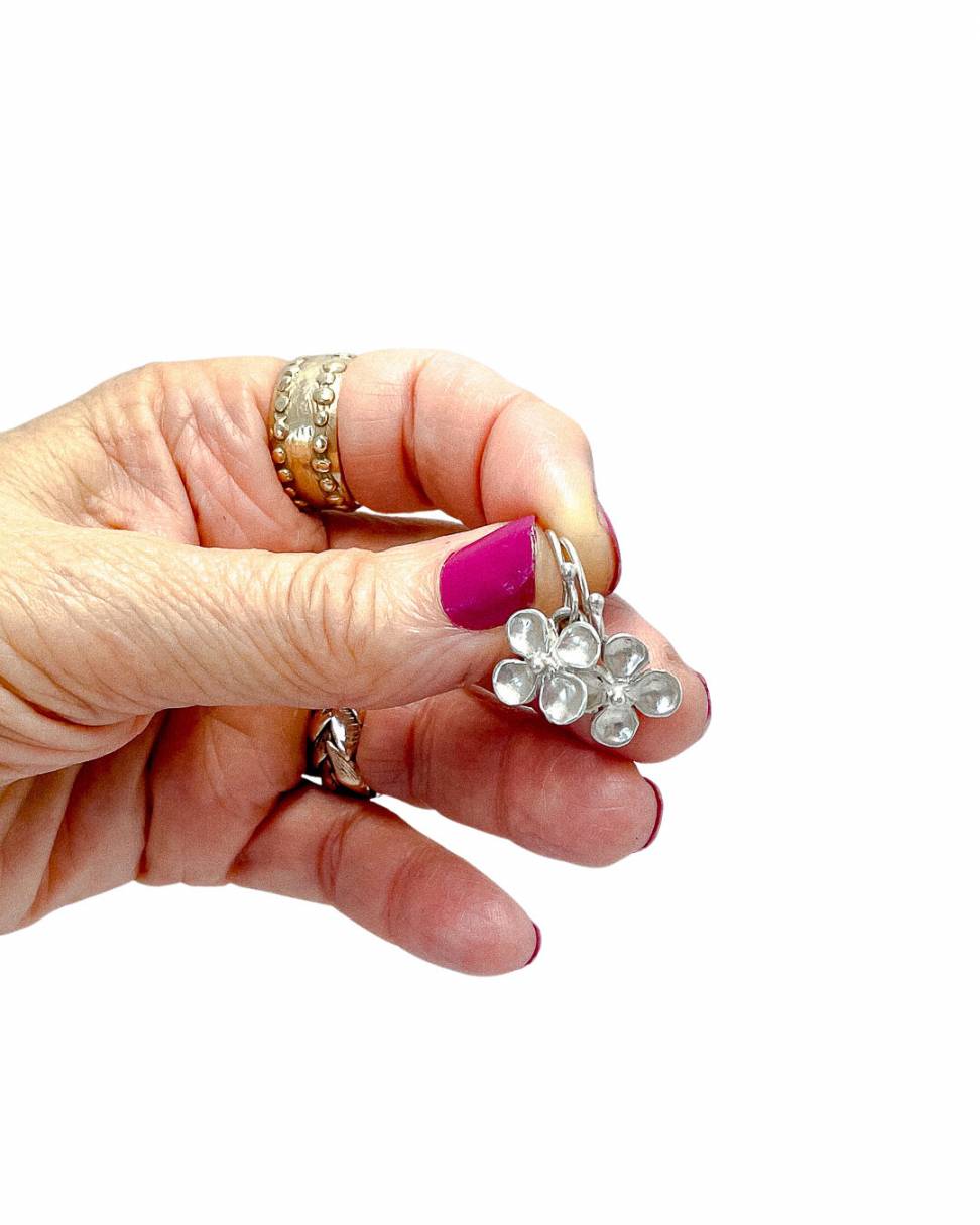 A pair of sterling silver hydrangea flower dangle earrings held in a hand