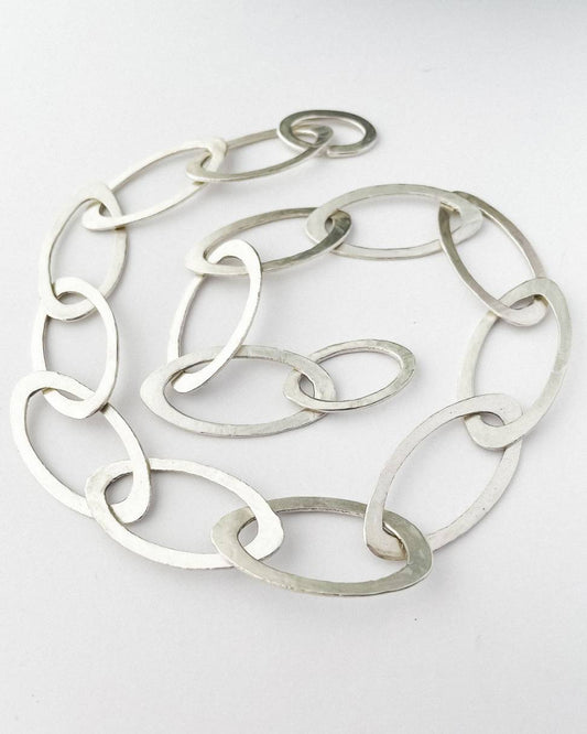 A close up of a hand fabricated Oval link chain in Sterling Silver laid in a spiral