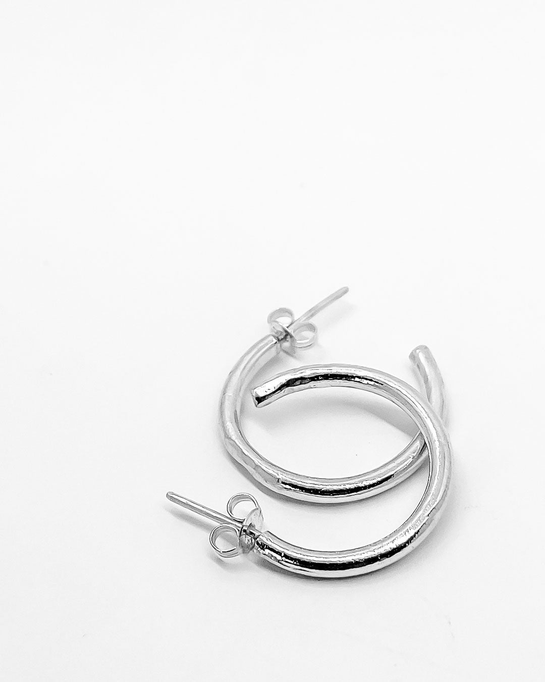 A pair of Sterling Silver Hoop earrings overlapping on a white surface
