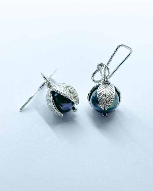 A pair of black pearls topped with Stylised leaves hung from artisan earring hooks
