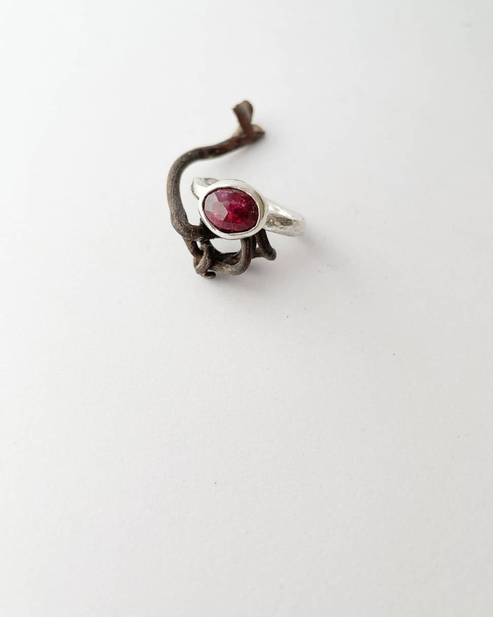 An organic Sterling Silver ring set with a large faceted oval ruby resting on a twisted vine