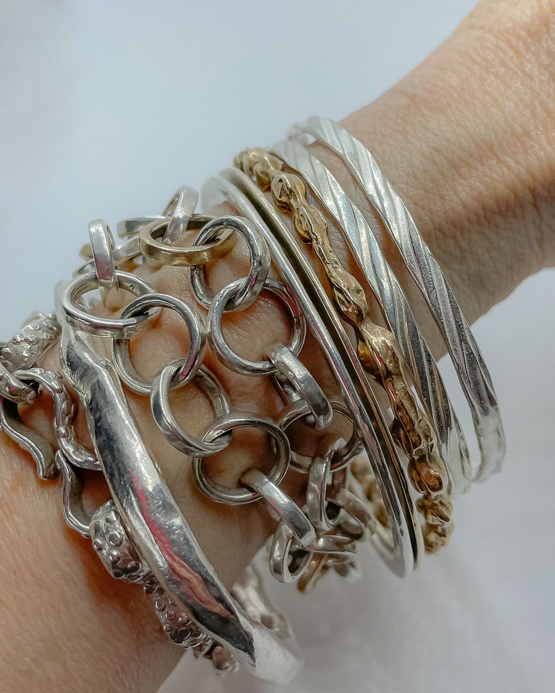 Two sterling Silver stacking bangles alongside a mix of chains and bangles on a womans wrist