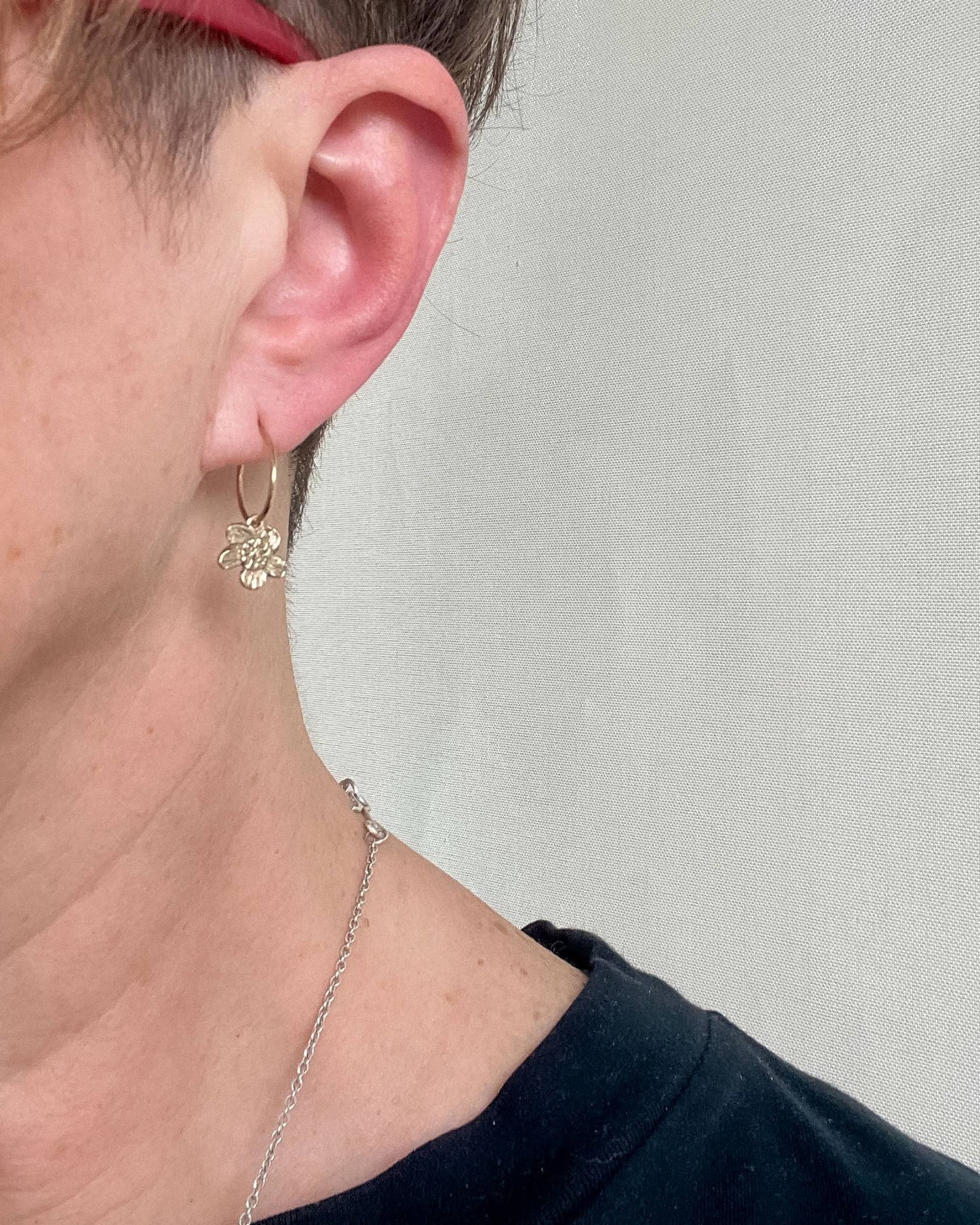 Showing the side profile of a woman wearing the 9ct Yellow Gold small hoop earring with a daisy charm