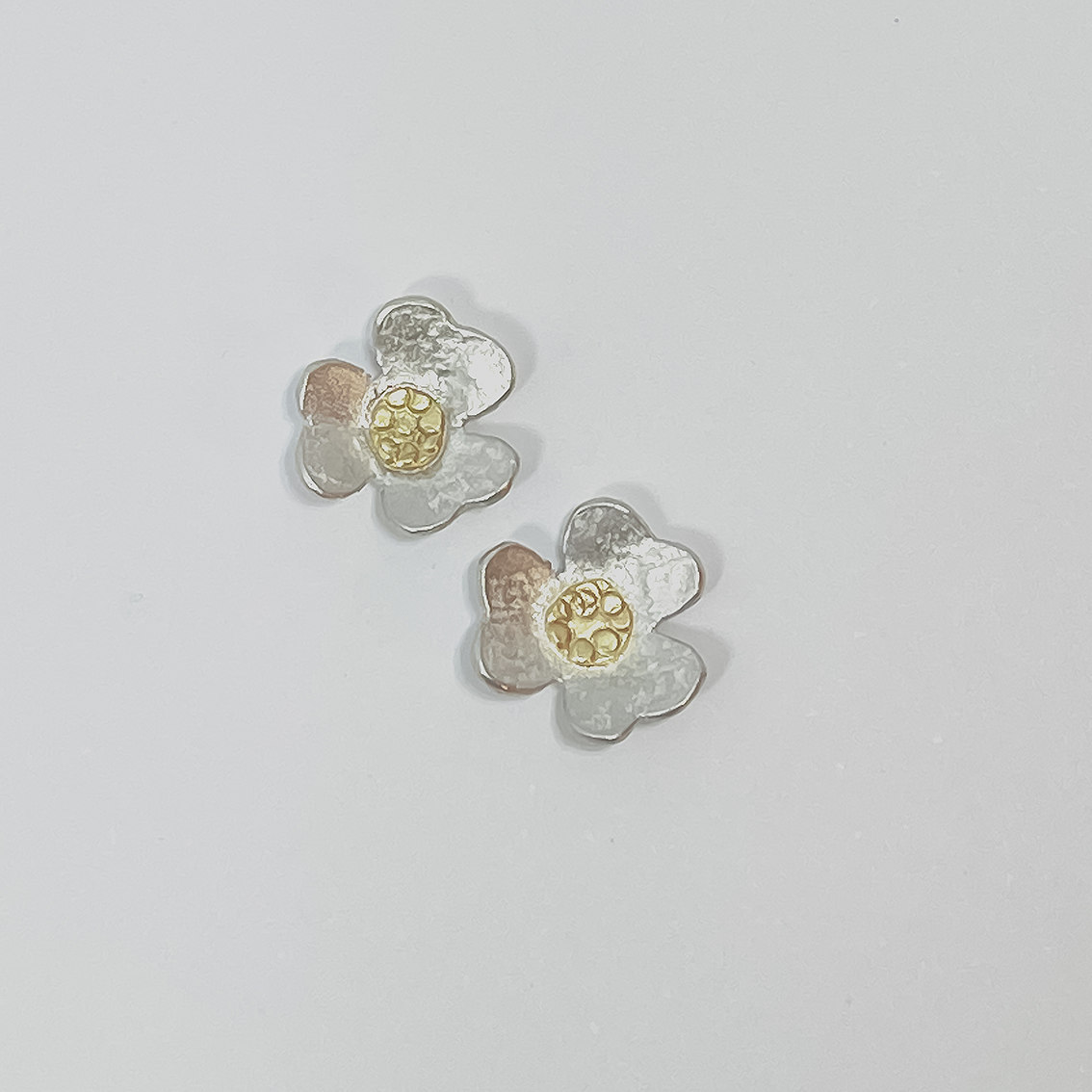 Front view of handcrafted Clover Stud Earrings showing the three-leaf flower design with 18ct gold centres against a light grey background.