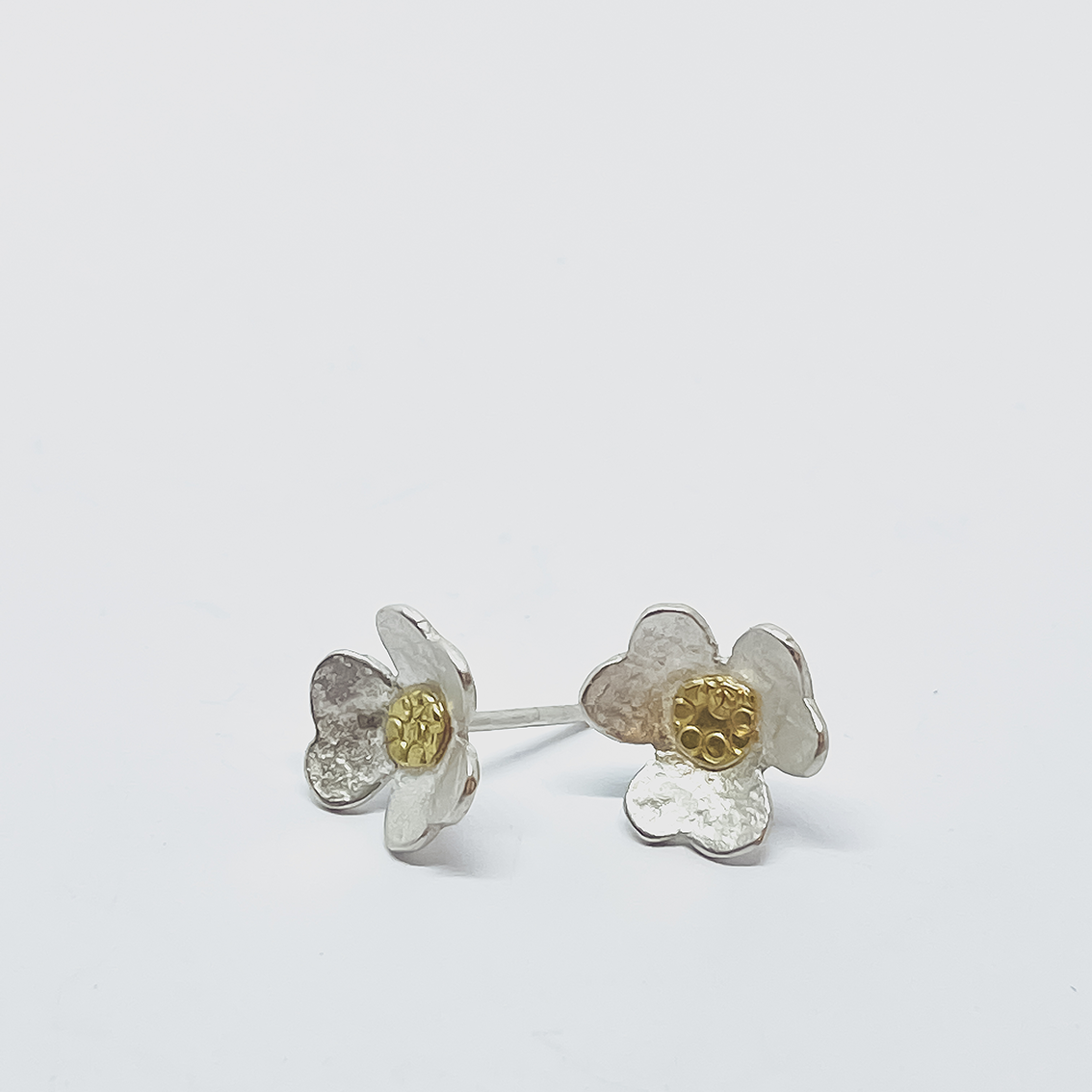 Pair of Clover Stud Earrings, one facing forward and one turned to the side showing sterling silver post and gold centre detail.